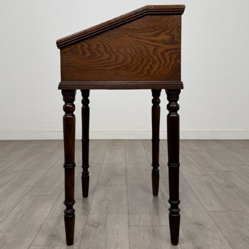 fig 3. A small dark oak Victorian clerks desk with a sloped hinged lid raised on tall turned legs.