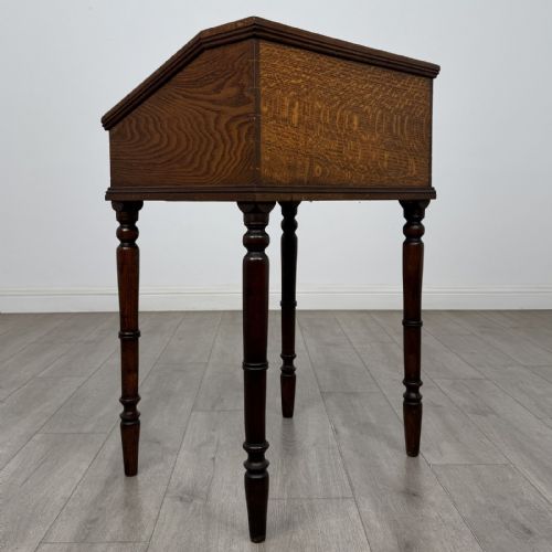 fig 4. A small dark oak Victorian clerks desk with a sloped hinged lid raised on tall turned legs.