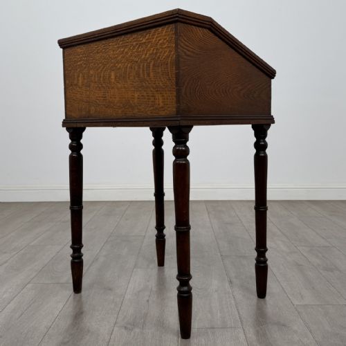 fig 6. A small dark oak Victorian clerks desk with a sloped hinged lid raised on tall turned legs.