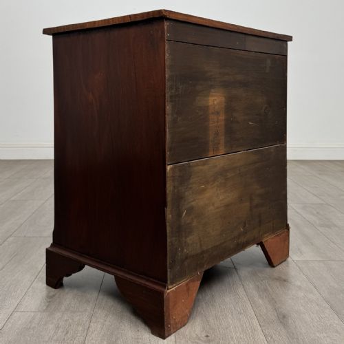 fig 3. A small Georgian-style dark mahogany chest of four drawers featuring brass ring pull handles and bracket feet.