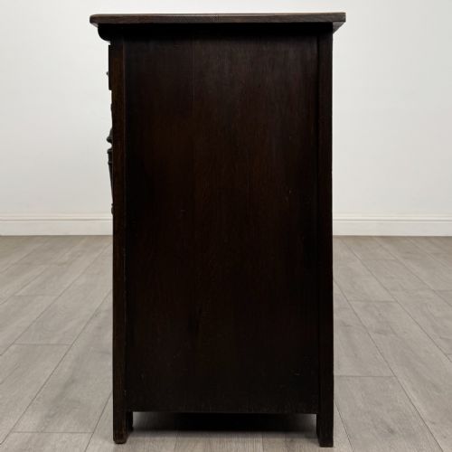 fig 2. A dark oak Jacobean style sideboard featuring two upper carved drawers and two cupboard doors decorated with geometric diamond panels.