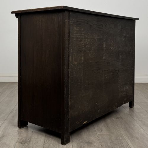 fig 3. A dark oak Jacobean style sideboard featuring two upper carved drawers and two cupboard doors decorated with geometric diamond panels.