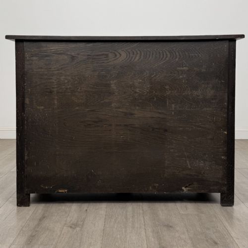fig 4. A dark oak Jacobean style sideboard featuring two upper carved drawers and two cupboard doors decorated with geometric diamond panels.