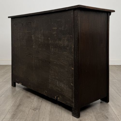 fig 5. A dark oak Jacobean style sideboard featuring two upper carved drawers and two cupboard doors decorated with geometric diamond panels.