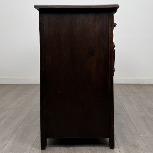 fig 6. A dark oak Jacobean style sideboard featuring two upper carved drawers and two cupboard doors decorated with geometric diamond panels.