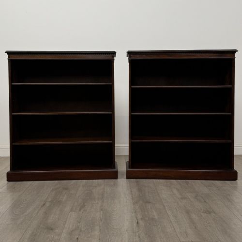 fig 1. A matching pair of dark brown oak open bookcases featuring carved cornices and four open tiers on plinth bases.