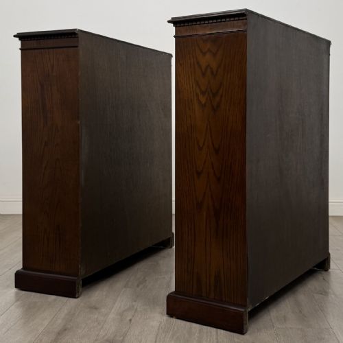 fig 3. A matching pair of dark brown oak open bookcases featuring carved cornices and four open tiers on plinth bases.