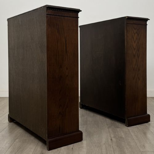 fig 5. A matching pair of dark brown oak open bookcases featuring carved cornices and four open tiers on plinth bases.