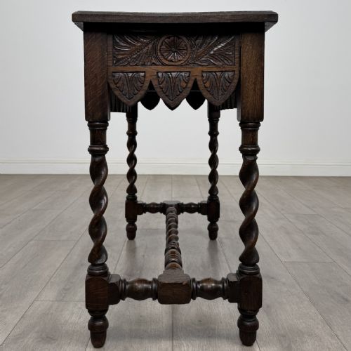 fig 2. A dark oak Victorian side table featuring hand-carved foliate drawers, a scalloped lower apron, and four barley twist legs joined by a central stretcher.