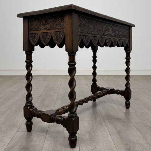 fig 3. A dark oak Victorian side table featuring hand-carved foliate drawers, a scalloped lower apron, and four barley twist legs joined by a central stretcher.