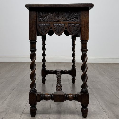 fig 6. A dark oak Victorian side table featuring hand-carved foliate drawers, a scalloped lower apron, and four barley twist legs joined by a central stretcher.