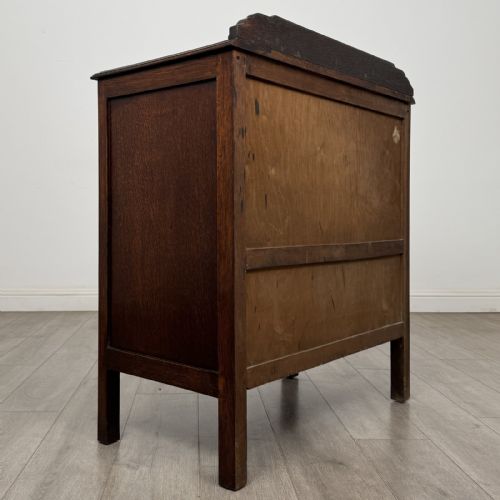 fig 3. A dark oak Arts and Crafts cupboard featuring double panelled doors with floral marquetry inlays above two wide drawers, finished with dark metal Celtic knot handles.