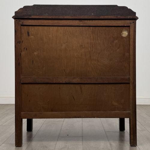 fig 4. A dark oak Arts and Crafts cupboard featuring double panelled doors with floral marquetry inlays above two wide drawers, finished with dark metal Celtic knot handles.