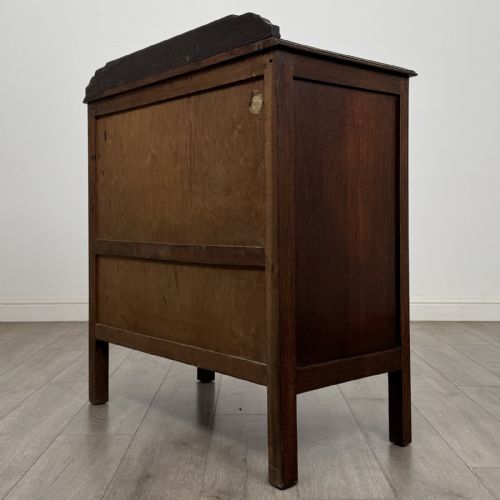 fig 5. A dark oak Arts and Crafts cupboard featuring double panelled doors with floral marquetry inlays above two wide drawers, finished with dark metal Celtic knot handles.