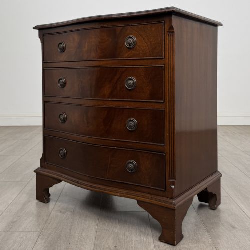 fig 1. A dark brown mahogany Georgian style chest of drawers featuring four drawers, fluted side pilasters, circular handles, and bracket feet.