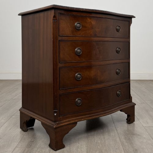 fig 7. A dark brown mahogany Georgian style chest of drawers featuring four drawers, fluted side pilasters, circular handles, and bracket feet.