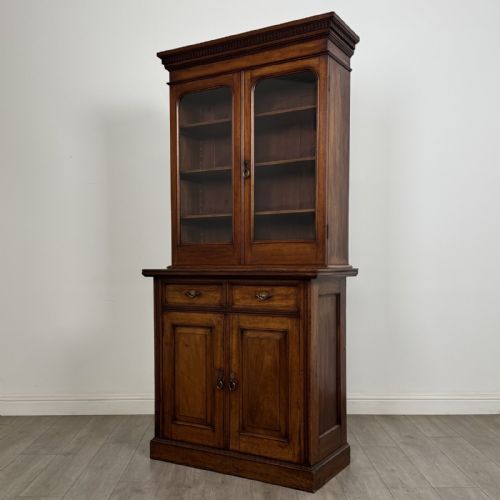 fig 1. A Victorian walnut glazed bookcase featuring a two-door glass display upper section above two drawers and a double cupboard base.