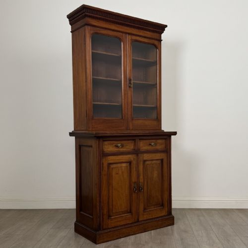 fig 7. A Victorian walnut glazed bookcase featuring a two-door glass display upper section above two drawers and a double cupboard base.