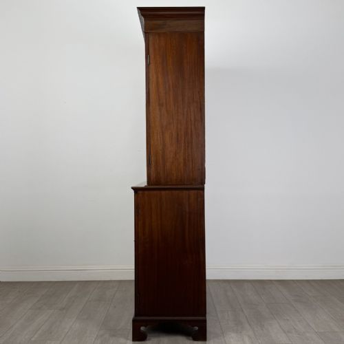fig 2. An antique Georgian mahogany two-section bookcase featuring upper double doors with geometric astragal glazing over lower solid panelled cupboard doors, supported by bracket feet.