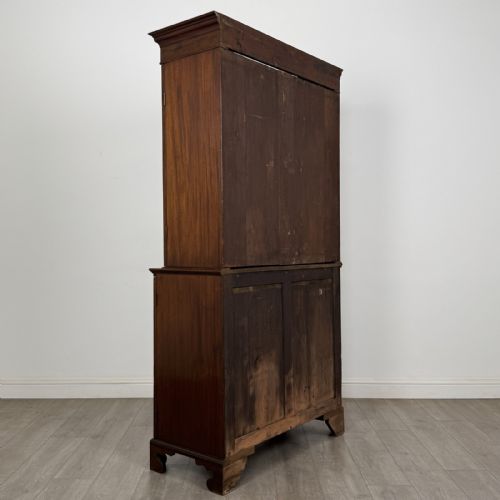 fig 3. An antique Georgian mahogany two-section bookcase featuring upper double doors with geometric astragal glazing over lower solid panelled cupboard doors, supported by bracket feet.