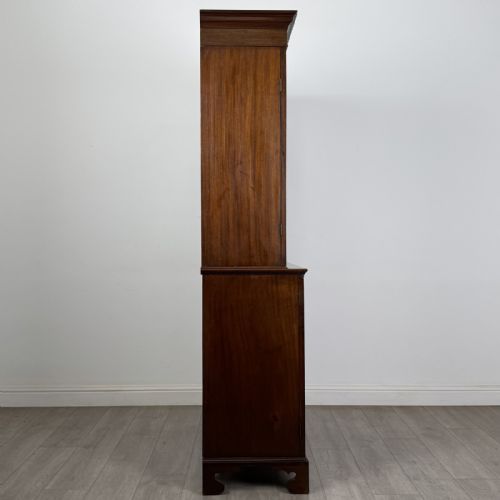 fig 6. An antique Georgian mahogany two-section bookcase featuring upper double doors with geometric astragal glazing over lower solid panelled cupboard doors, supported by bracket feet.
