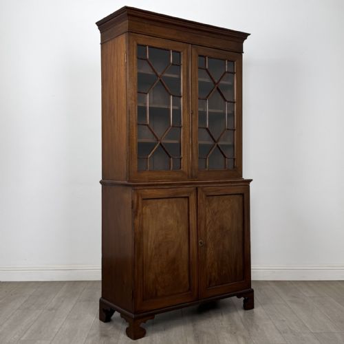 fig 7. An antique Georgian mahogany two-section bookcase featuring upper double doors with geometric astragal glazing over lower solid panelled cupboard doors, supported by bracket feet.