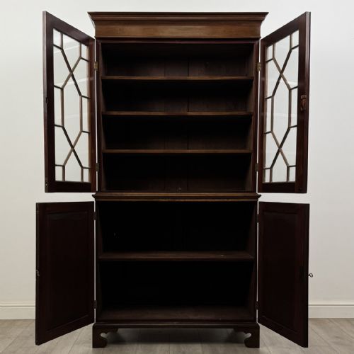 fig 8. An antique Georgian mahogany two-section bookcase featuring upper double doors with geometric astragal glazing over lower solid panelled cupboard doors, supported by bracket feet.