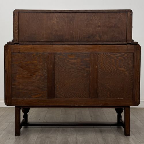 fig 4. A medium brown oak Jacobean style sideboard featuring a raised gallery shelf, carved side columns, three central drawers, flanking cupboard doors, and bulbous turned legs connected by a stretcher.