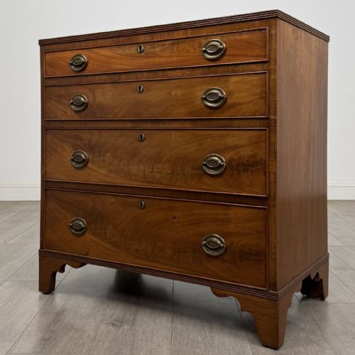 fig 1. A straight-front Georgian style mahogany chest features four full-width drawers with decorative oval brass drop handles, keyhole escutcheons, and bracket feet.