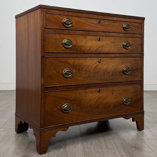 fig 7. A straight-front Georgian style mahogany chest features four full-width drawers with decorative oval brass drop handles, keyhole escutcheons, and bracket feet.