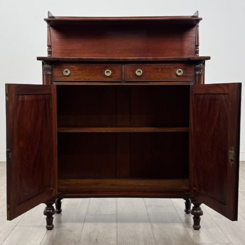 fig 1. A Regency mahogany chiffonier featuring a raised shelf, two drawers with brass ring handles, and a double-door cupboard flanked by carved columns on turned feet.