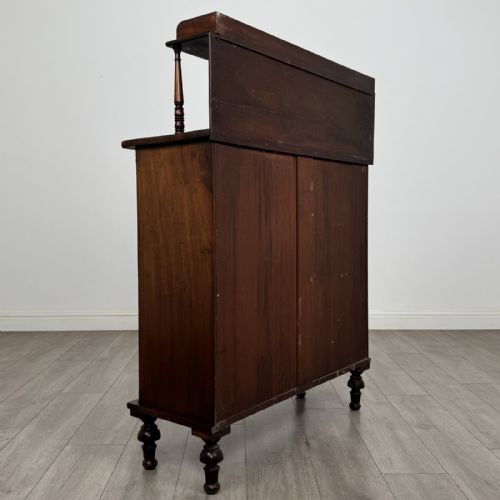 fig 4. A Regency mahogany chiffonier featuring a raised shelf, two drawers with brass ring handles, and a double-door cupboard flanked by carved columns on turned feet.