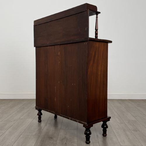 fig 6. A Regency mahogany chiffonier featuring a raised shelf, two drawers with brass ring handles, and a double-door cupboard flanked by carved columns on turned feet.