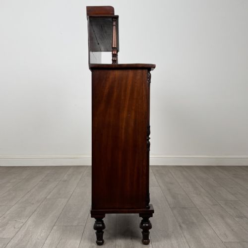 fig 7. A Regency mahogany chiffonier featuring a raised shelf, two drawers with brass ring handles, and a double-door cupboard flanked by carved columns on turned feet.