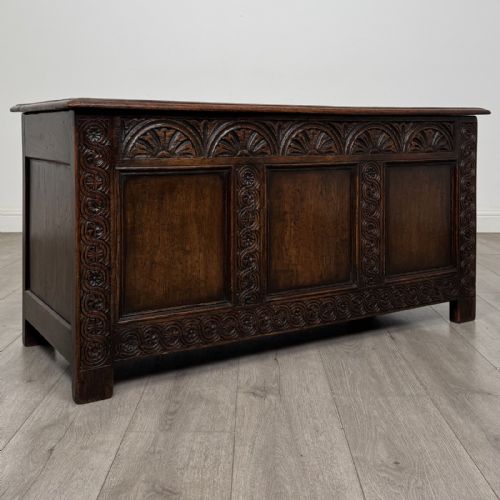 fig 7. A dark oak Jacobean style blanket box featuring a carved lunette frieze, three panelled sections, and guilloche carving along the stiles.