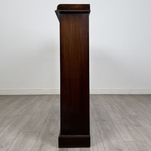 fig 3. An Edwardian dark oak display cabinet featuring three doors with geometric leaded glass panels and interior wooden shelves.