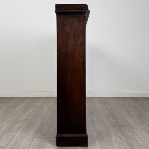 fig 7. An Edwardian dark oak display cabinet featuring three doors with geometric leaded glass panels and interior wooden shelves.