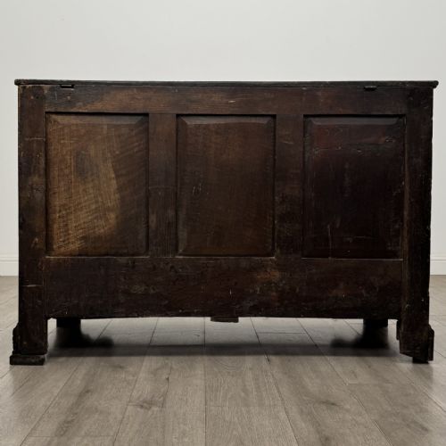 fig 4. An eighteenth-century dark oak mule chest featuring three raised panels on the front enclosure above two drawers with brass handles, raised on bracket feet.