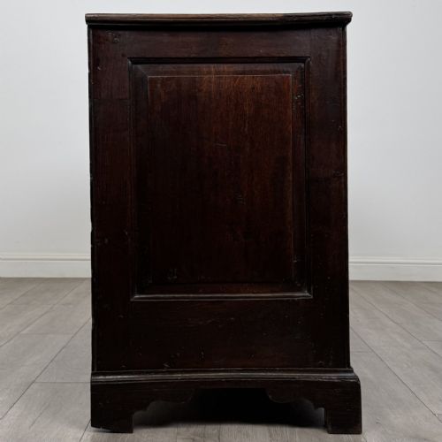 fig 6. An eighteenth-century dark oak mule chest featuring three raised panels on the front enclosure above two drawers with brass handles, raised on bracket feet.