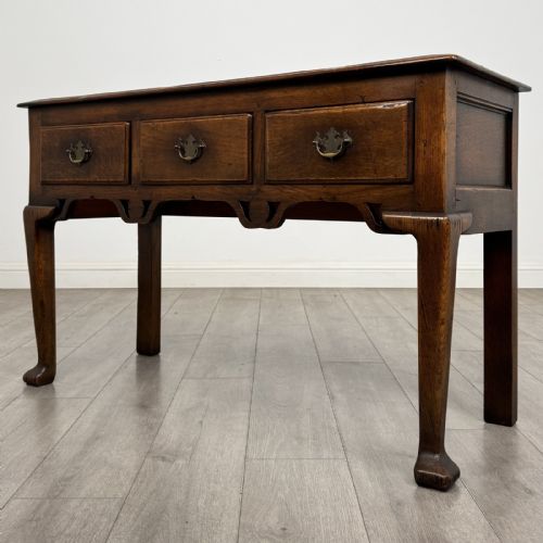 fig 1. A Georgian style dark oak dresser base featuring three drawers with brass swan-neck handles, a shaped apron, and cabriole front legs.