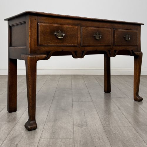 fig 7. A Georgian style dark oak dresser base featuring three drawers with brass swan-neck handles, a shaped apron, and cabriole front legs.