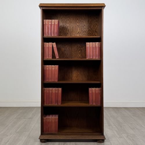 fig 1. A tall dark oak open bookcase with five tiered compartments, adjustable shelves, a moulded cornice, and flattened bun feet.