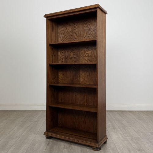 fig 2. A tall dark oak open bookcase with five tiered compartments, adjustable shelves, a moulded cornice, and flattened bun feet.