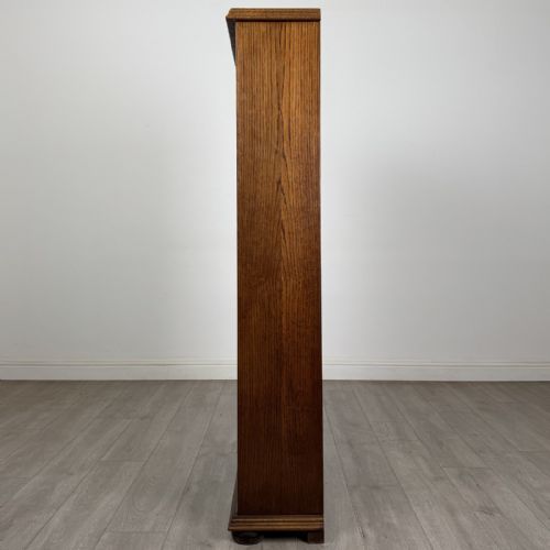 fig 3. A tall dark oak open bookcase with five tiered compartments, adjustable shelves, a moulded cornice, and flattened bun feet.