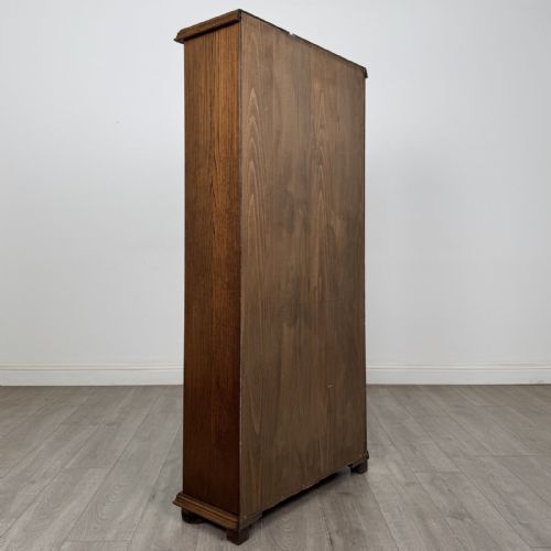 fig 4. A tall dark oak open bookcase with five tiered compartments, adjustable shelves, a moulded cornice, and flattened bun feet.