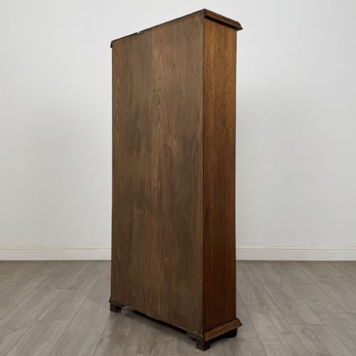 fig 6. A tall dark oak open bookcase with five tiered compartments, adjustable shelves, a moulded cornice, and flattened bun feet.
