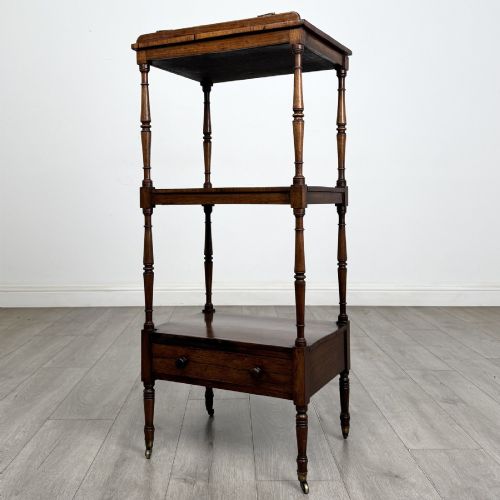 fig 2. An antique Regency rosewood three-tiered whatnot featuring an adjustable angled reading slope top, slender turned upright supports, a bottom drawer, and brass castors.