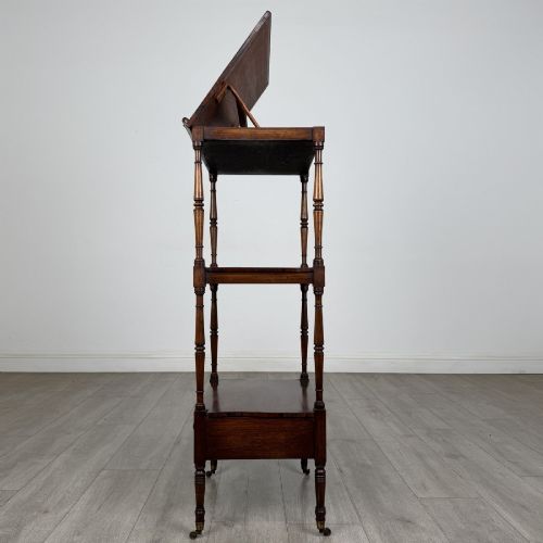 fig 3. An antique Regency rosewood three-tiered whatnot featuring an adjustable angled reading slope top, slender turned upright supports, a bottom drawer, and brass castors.