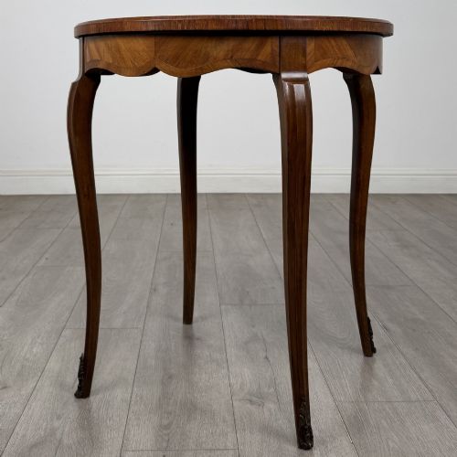 fig 1. A circular French Louis XV style lamp table featuring slender cabriole legs, marquetry wood grain pattern, an undulating apron, and metal sabot feet.