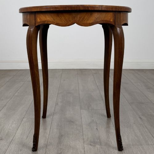 fig 2. A circular French Louis XV style lamp table featuring slender cabriole legs, marquetry wood grain pattern, an undulating apron, and metal sabot feet.